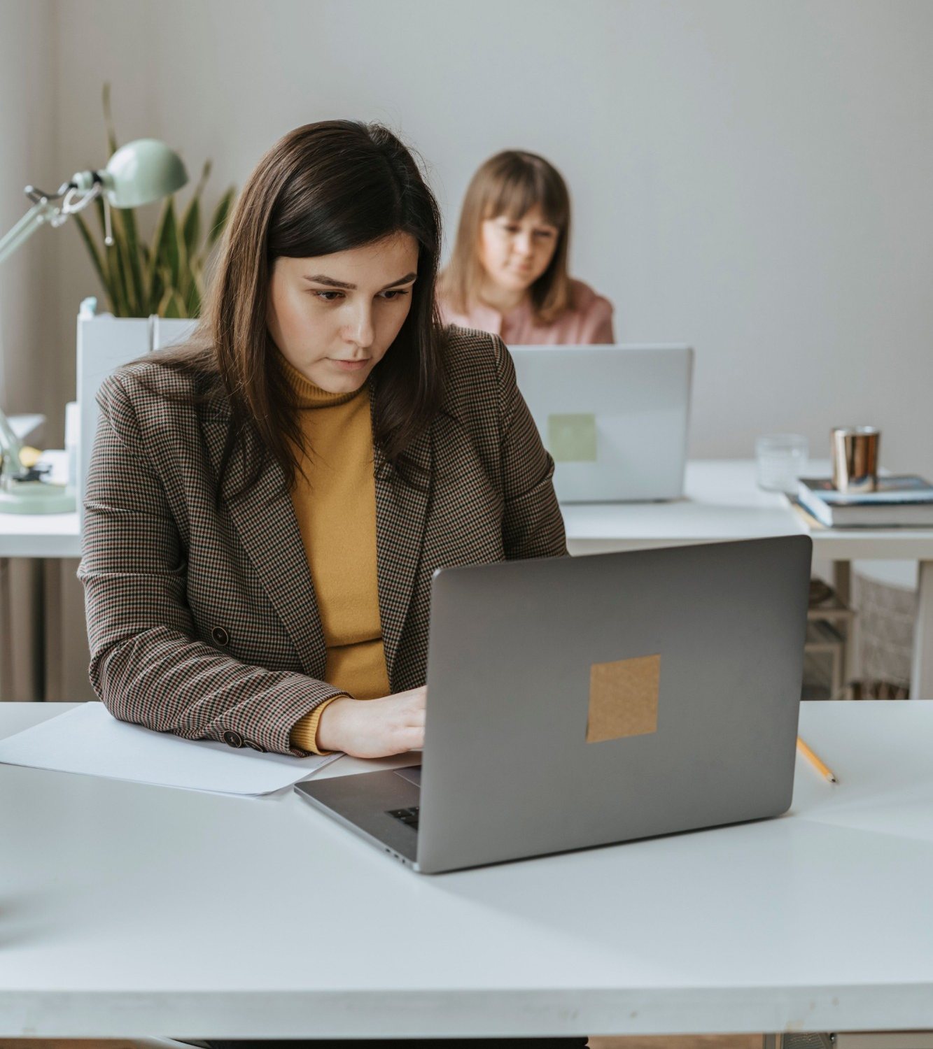 An analyst working on her laptop at a shared office desk